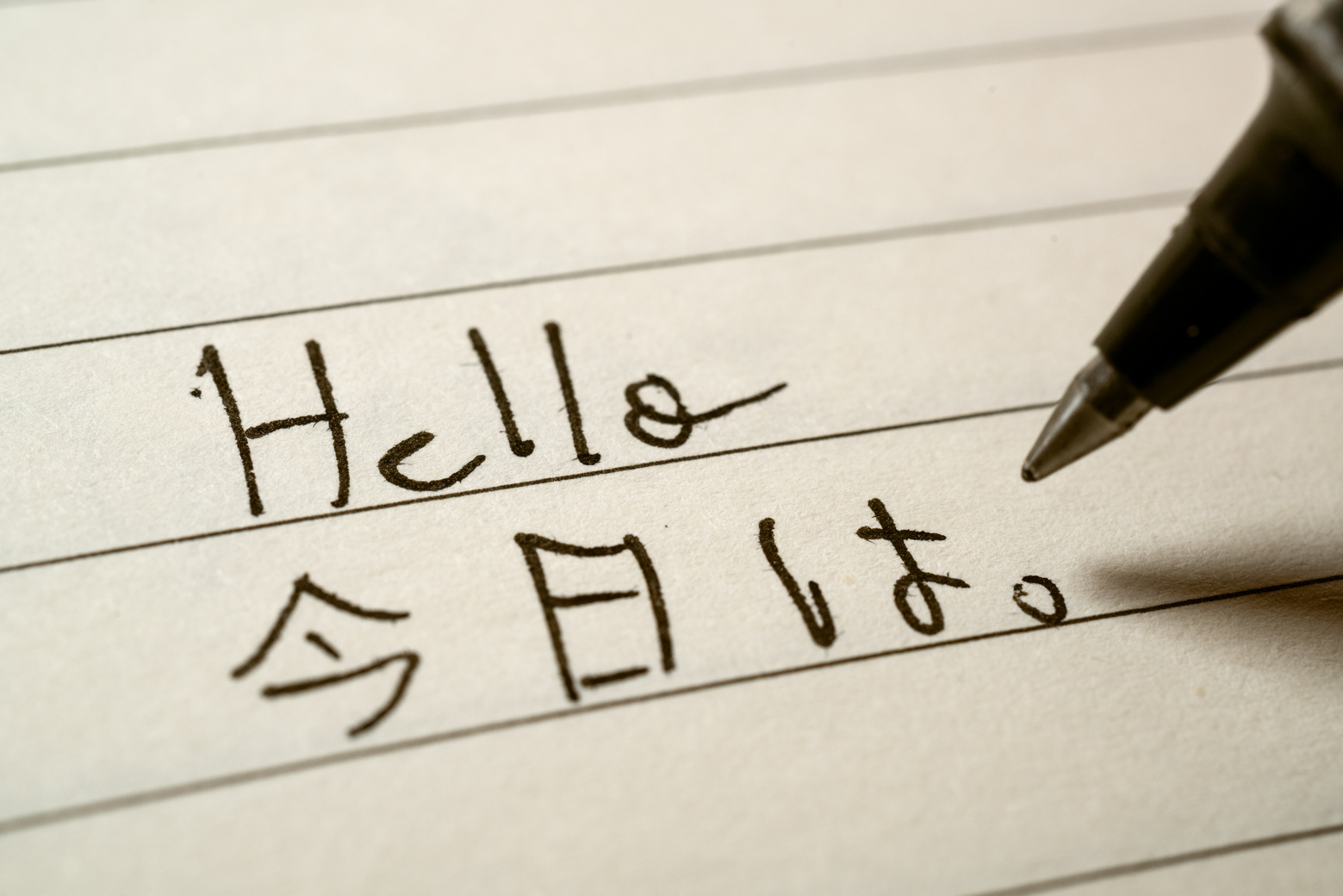 Beginner Japanese language learner writing Hello word in Japanese kanji characters on a notebook close-up shot
